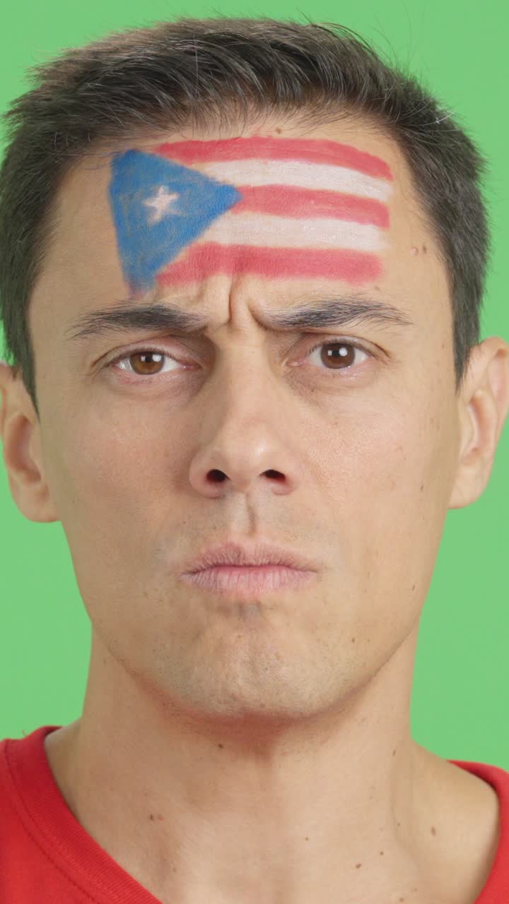 Serious man with a puerto rican flag painted on the face