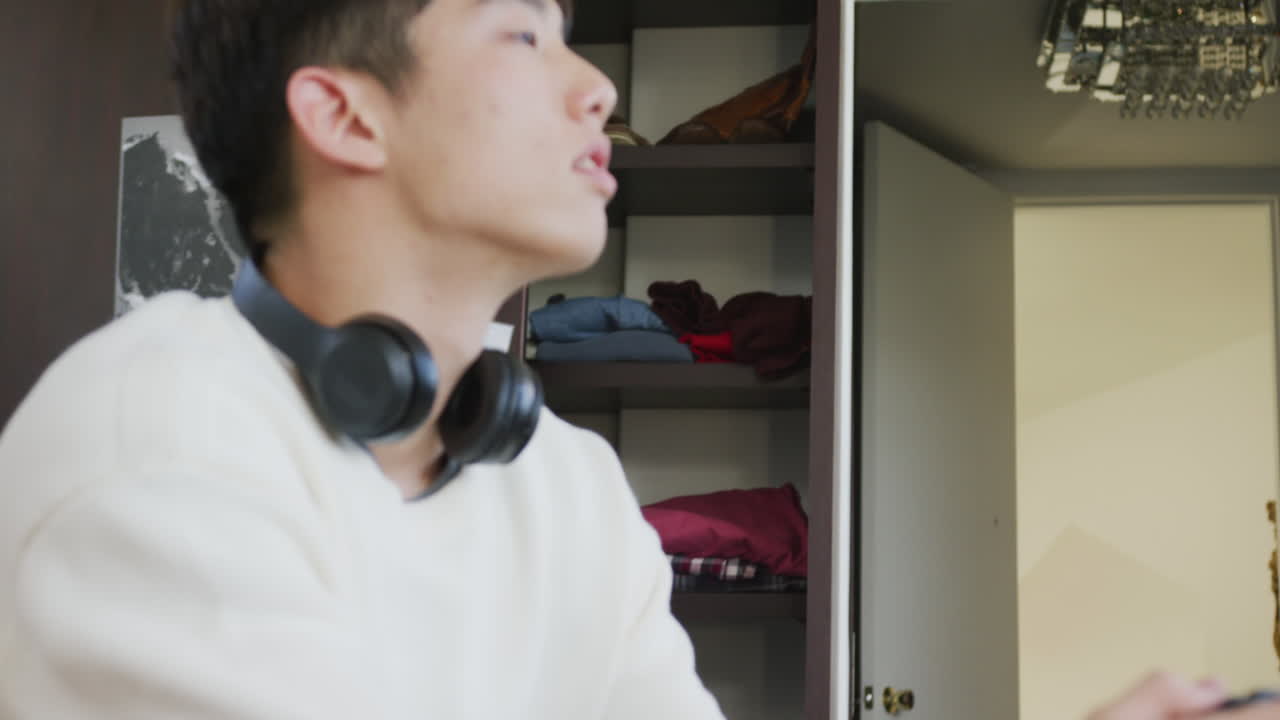 집 에서 소파 에 앉아 비디오 게임 을 하는 아시아 소년