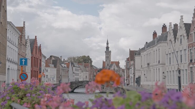 Quest'immagine cattura una serena vista da un ponte storico di Bruges, che si affaccia su un pittoresco canale fiancheggiato da incantevoli edifici tradizionali fiamminghi