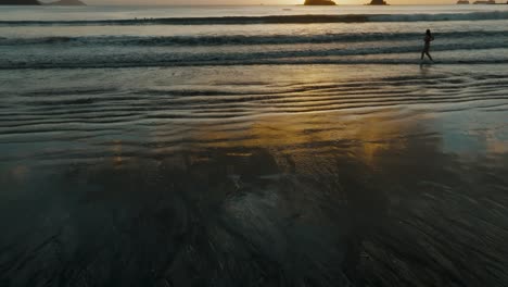 Reflejos-Del-Atardecer-En-La-Orilla-Del-Mar-Con-Turistas-En-La-Playa-De-Costa-Rica