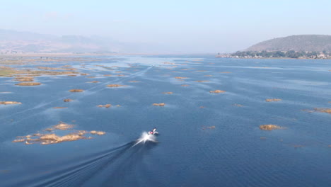 Single-traditional-long-boat-on-full-speed-cruising-over-Moebyel-Lake-in-Myanmar