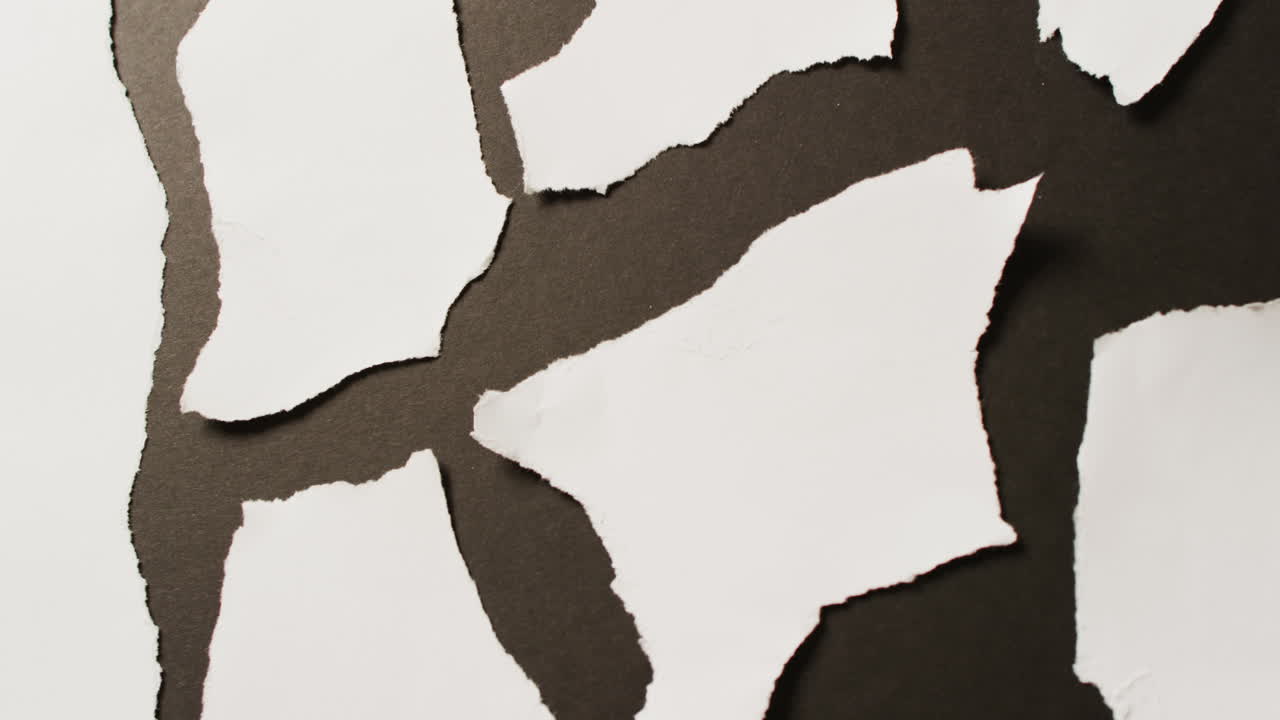 Video of close up of multiple white paper pieces on black background