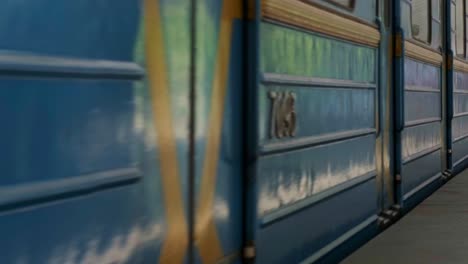 cinemagraph - blue subway train with people inside moving fast, view from metro station. close up for windows of subway train passing fast