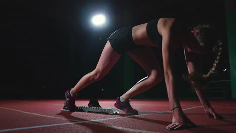 female hispanic athlete training at running track in the dark. slow motion