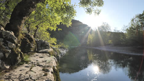 sun setting over a river with trees on a cliff herault france