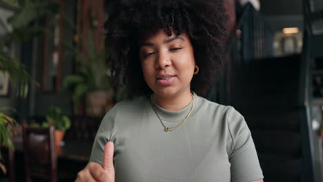 smiling woman giving thumbs up in a cafe