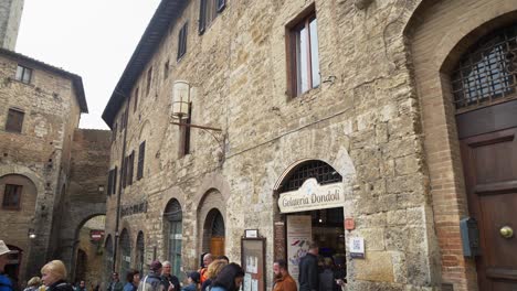 Customers-In-Popular-Ice-Cream-Shop-In-Piazza-della-Cisterna,-San-Gimignano,-Italy