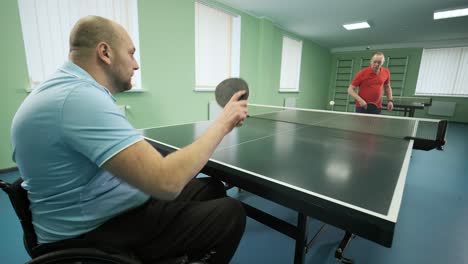 a man in a wheelchair plays ping pong. people with disabilities play table tennis. rehabilitation of the disabled. paralympic sport.