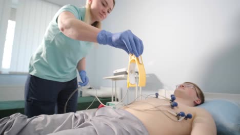 cardiac examination in a hospital with a professional cardiograph. the patient lies on a bed with connected sensors.