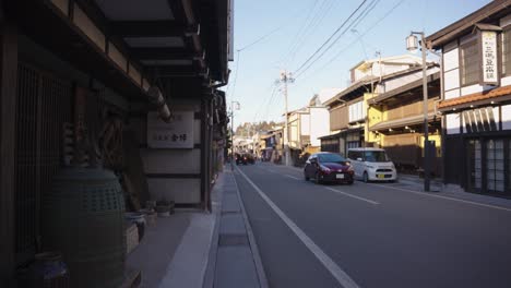 City-Streets-of-Takayama,-Cars-Driving-Past-Old-Homes-and-Shops