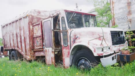 an old garbage truck left to the elements in an open field