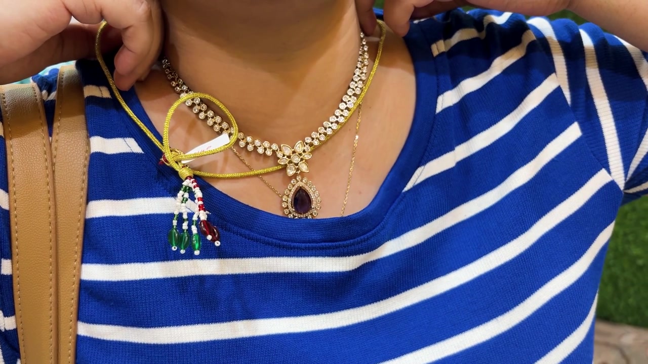 Donna che prova un'elegante collana con pendente di diamanti in uno showroom di gioielleria di lusso.