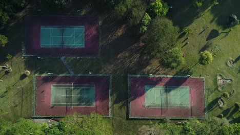 drone with camera going uphill shows tennis courts with nature around in public park, sports, health, leisure, in 4k resolution