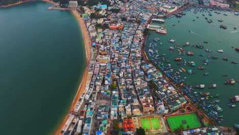 drone shot traveling forward of a city built on an isthmus with an harbor and a popular beach during the day