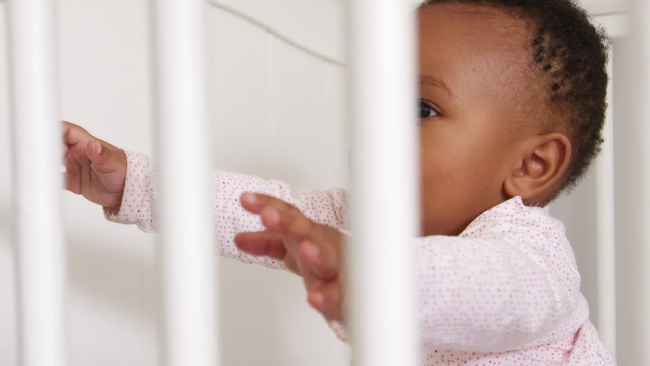 Bambina felice che gioca nella culla della cameretta ripresa al rallentatore.