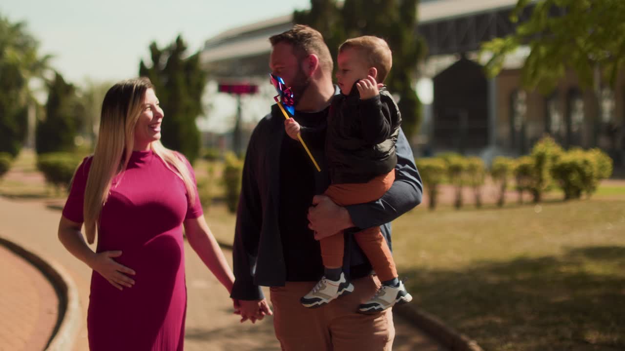 Family walking in a park with a pregnant mother and child
