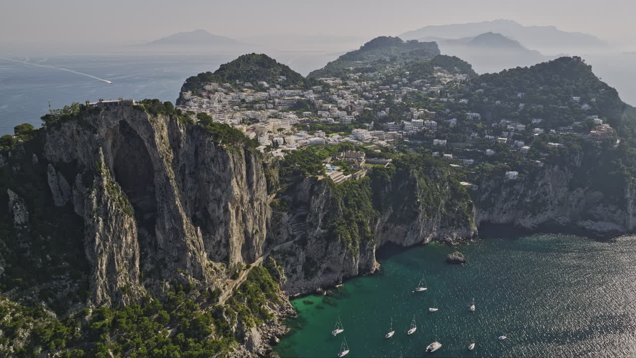 capri, italia drones aéreos v4 vuelan a lo largo de los dramáticos acantilados marinos capturando el terreno rocoso costero, la encantadora ciudad al lado del acantilado y el agua turquesa cristalina en verano - filmado con mavic 3 cine - mayo 2023