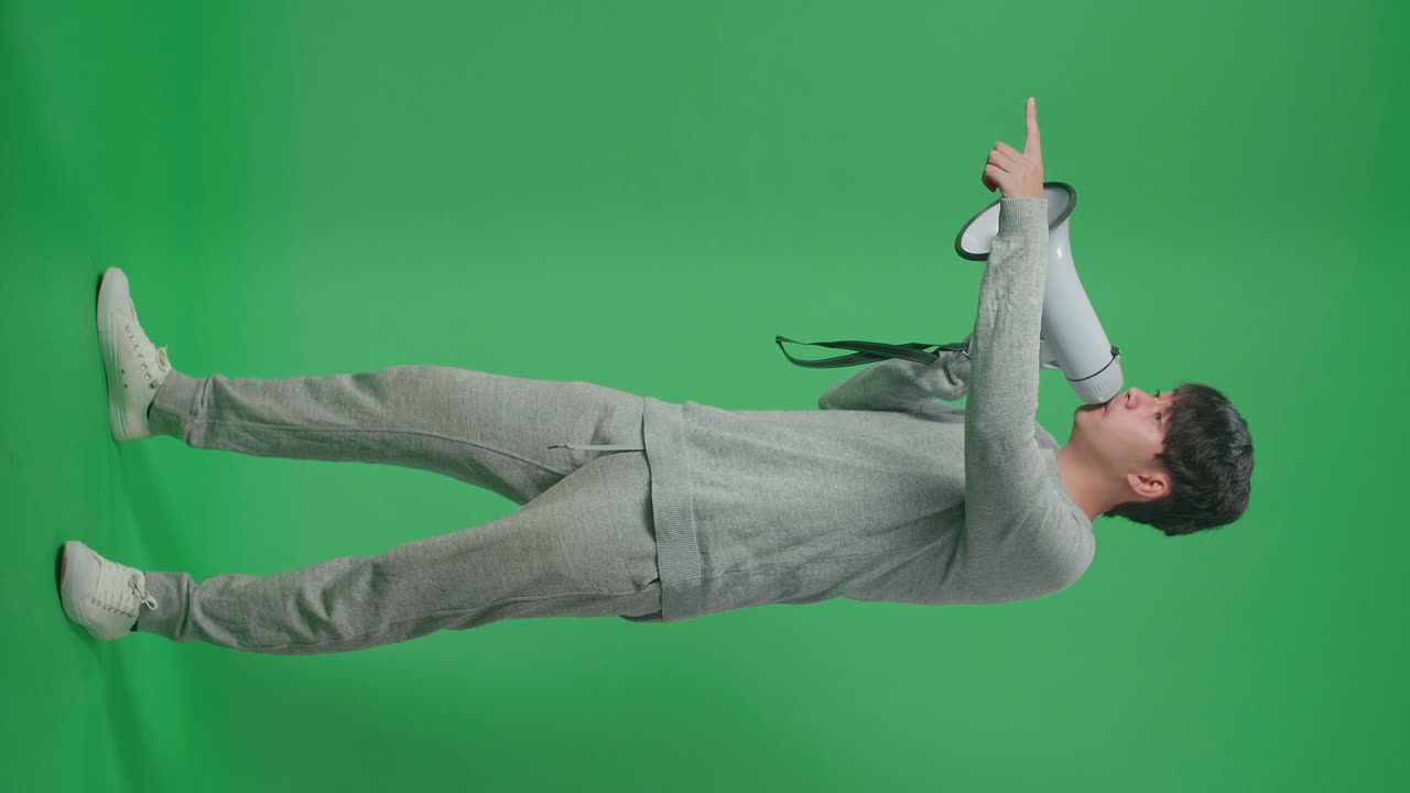 Full Body Of Side View Of An Asian Man Speaking On Megaphone In The Green Screen Studio