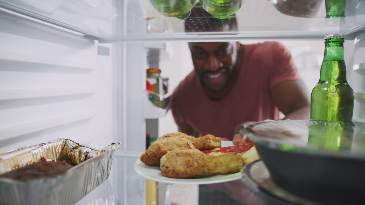 vista mirando desde el interior del refrigerador lleno de comida para llevar cuando el hombre abre la puerta