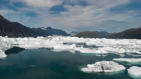 Drone-Aerial-View,-Icebergs-in-Glacial-Water-at-Alaskan-Coastline-on-Sunny-Day