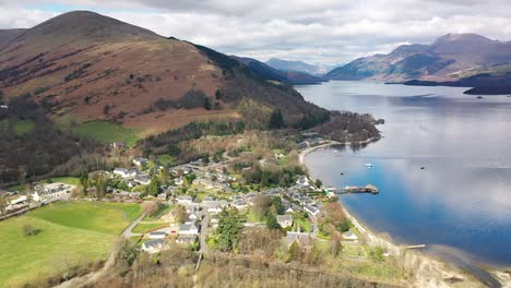 aerial angle of pan around village of luss loch lomond pan from ben lomond to reveal the village and valley behind in early spring