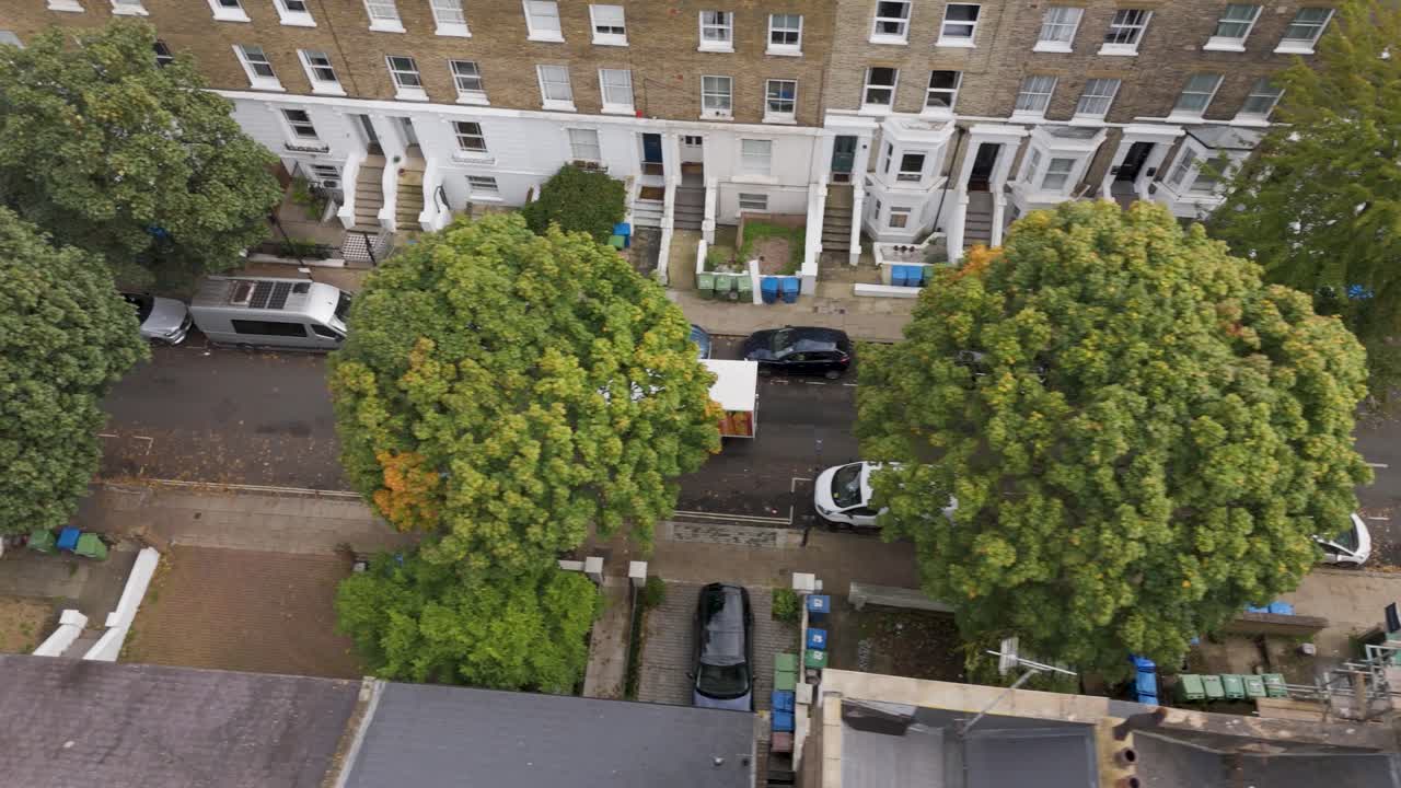 Tracking aerial view of a supermarket delivery van navigating city residential streets, London, UK, October 2024