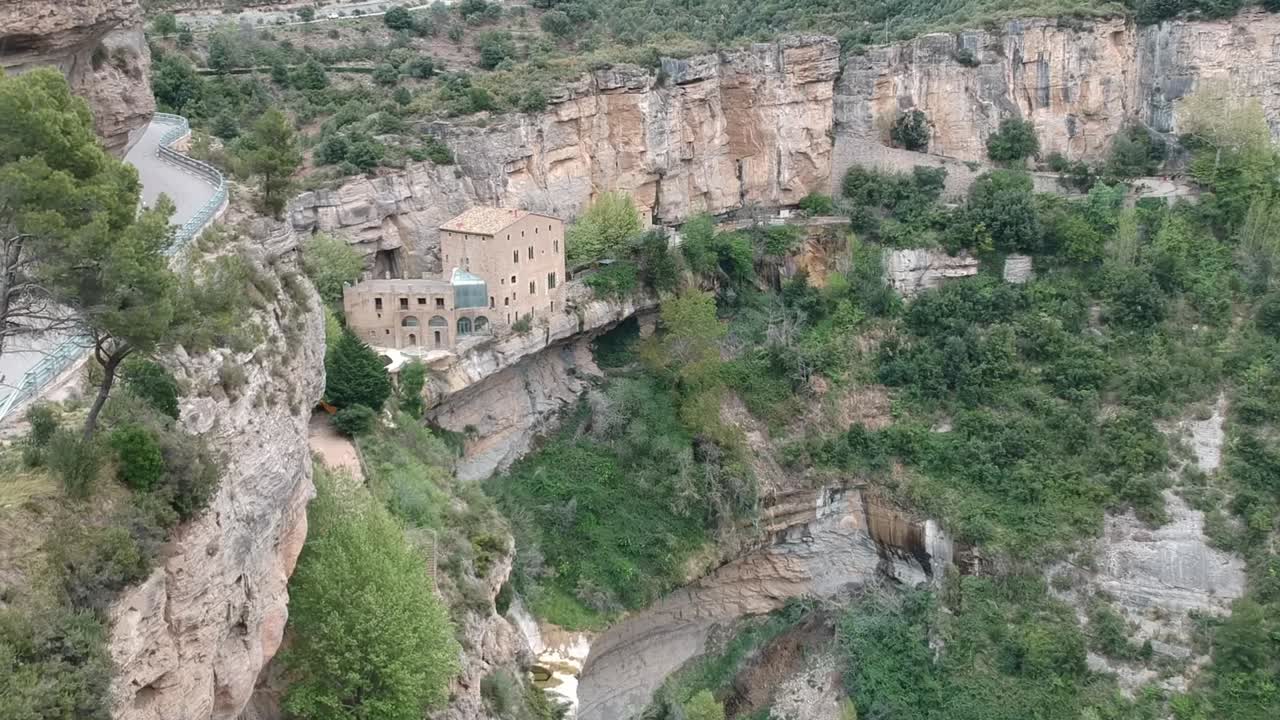 Vedute aeree di una cascata con una grotta e un vecchio edificio in Catalogna, Spagna