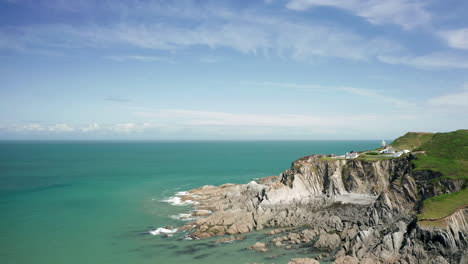 Aerial-Shot-of-a-Lighthouse-Perched-above-a-Rocky-Coastline