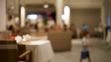 un niño se mueve a través de un entorno de restaurante borroso, creando una atmósfera dinámica y animada con iluminación suave