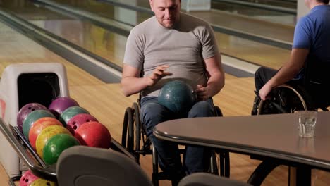 two young disabled men in wheelchairs playing bowling in the club