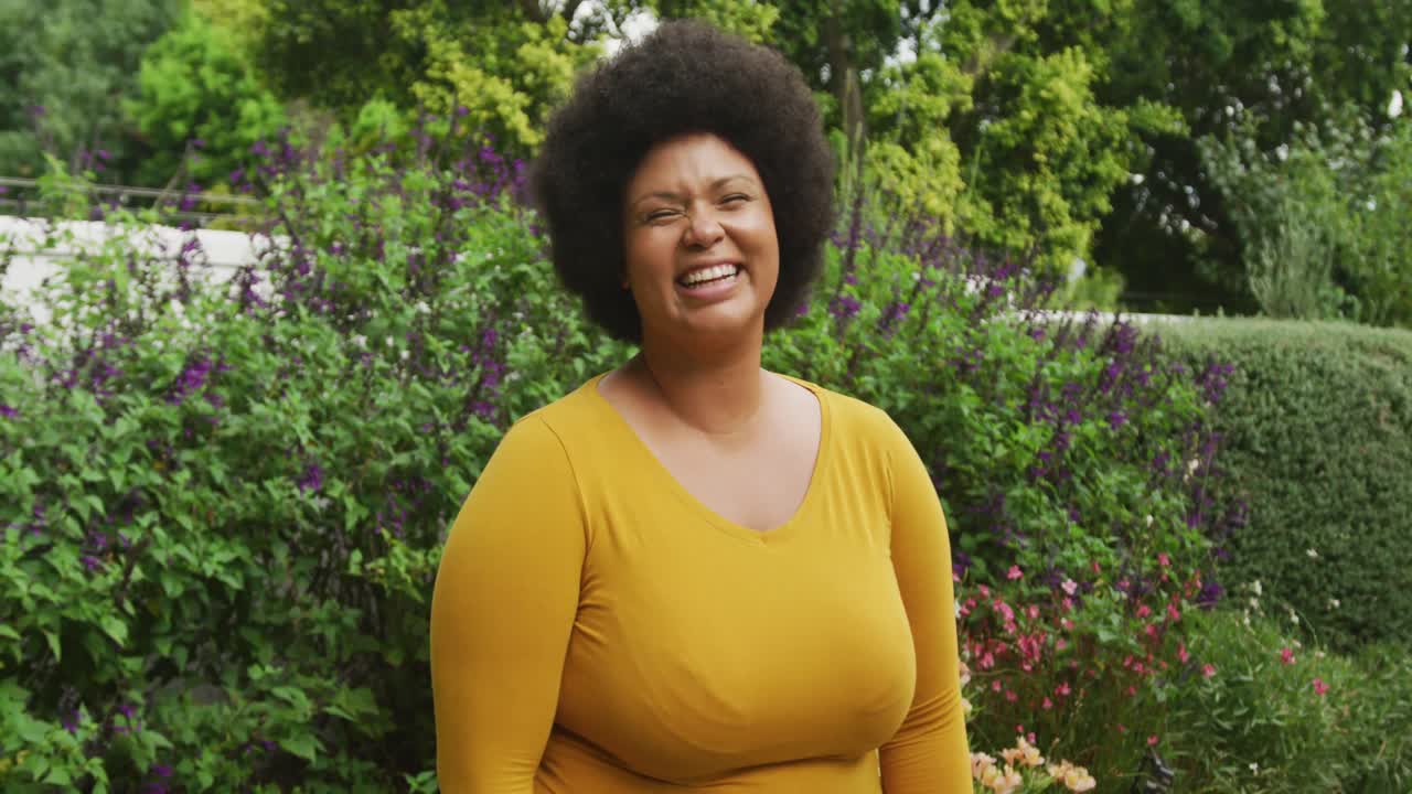 video de una feliz mujer afroamericana de tamaño grande de pie en el jardín
