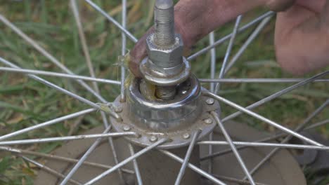 a man applyes fatty grease to the axle of a bicycle wheel with his fingers