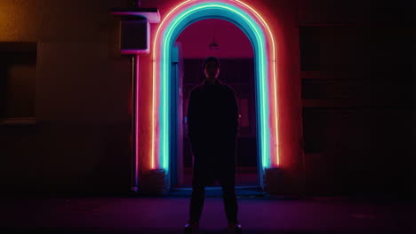 person silhouetted in a vibrant neon archway at night
