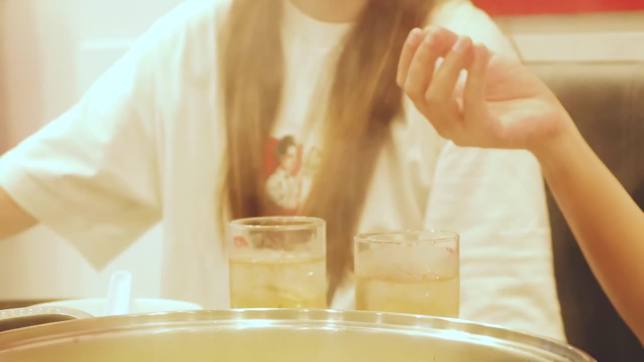 Close-up of hands arranging food items and drinks on a dining table.