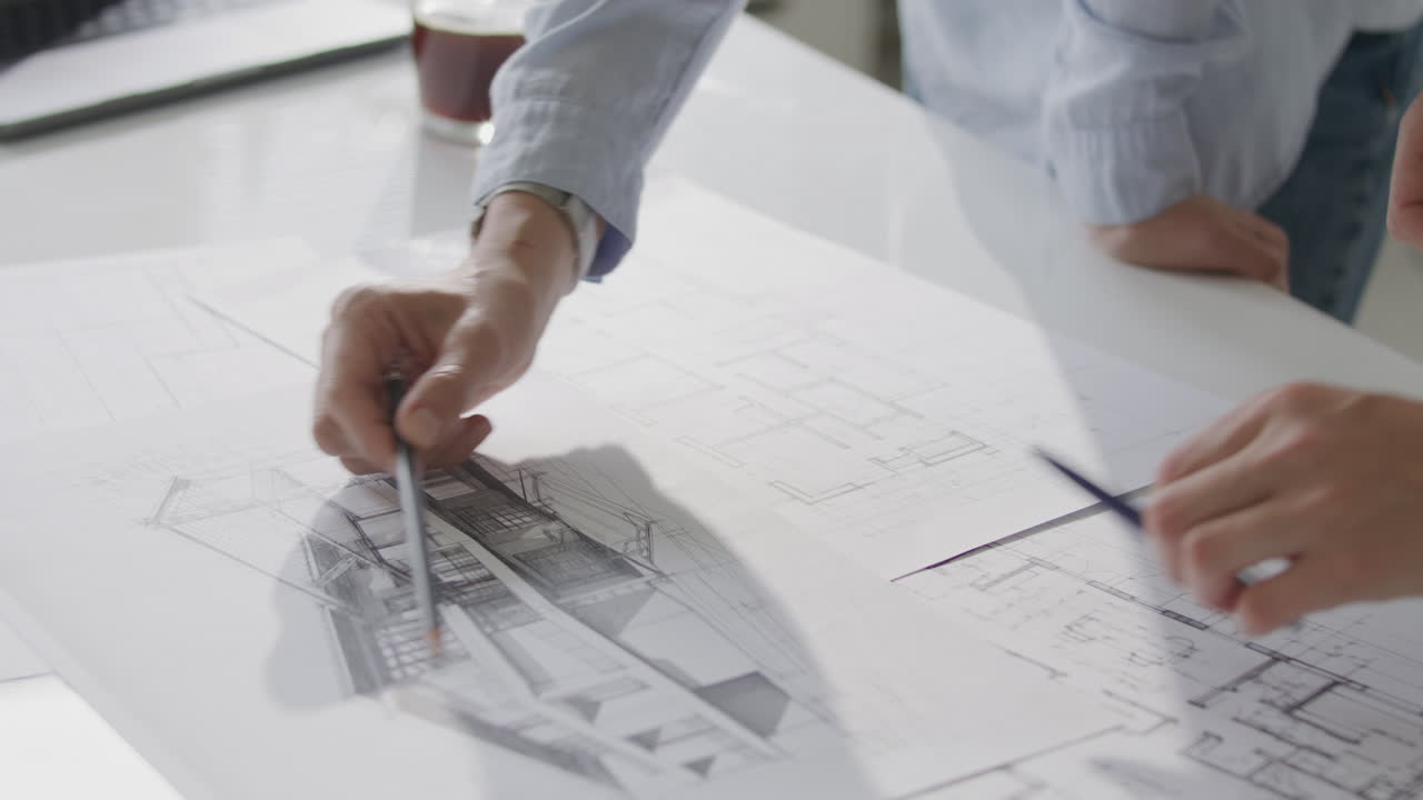 Close Up of Architects Discussing Technical Building Sketch on Desk