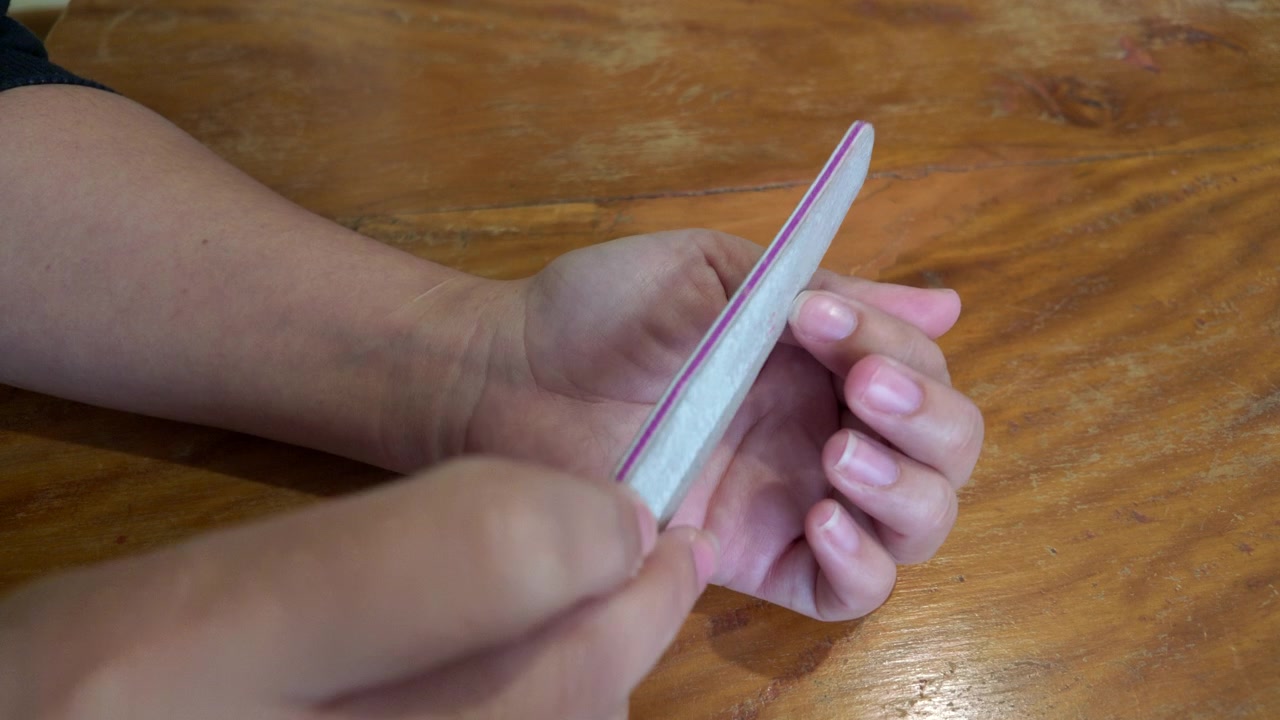 Primo piano dettagliato di una donna che si lima le unghie durante una manicure e una routine di cura personale femminile.