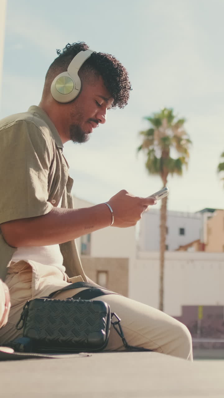 Man with headphones using phone outdoors