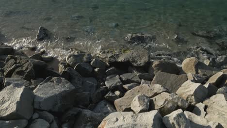 Aerial-crane-shot-of-large-stones-on-a-coastline-looking-out-to-sea