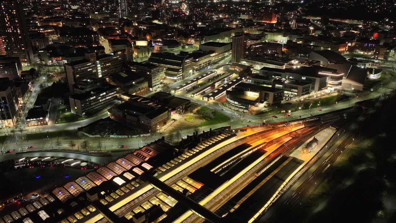 Sinking aerial of Sheffield train station and city lights at night