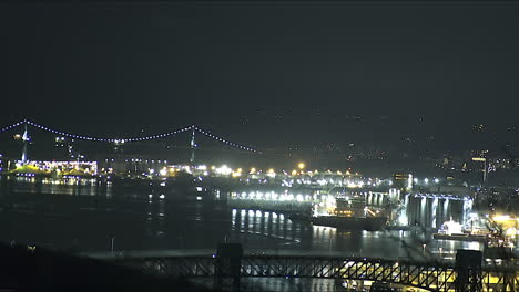 nighttime view of a lit-up port and suspension bridge