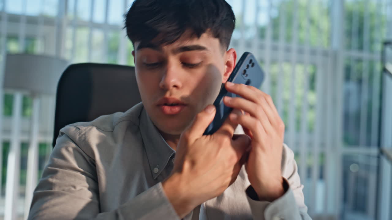 Nervous man negotiating mobile phone at office closeup. Businessman talking