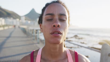 retrato de una mujer afroamericana en ropa deportiva descansando en el paseo marítimo por el mar