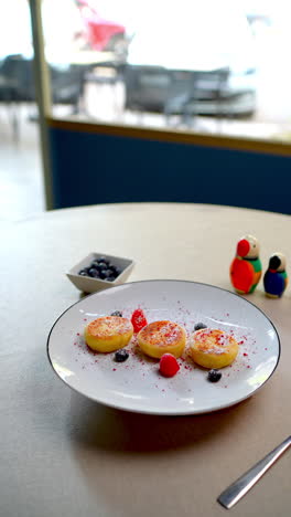 delicious syrniki, typical eastern european cheese pancakes, served on a white plate and decorated with raspberries, blueberries, and powdered sugar, perfect for breakfast or brunch