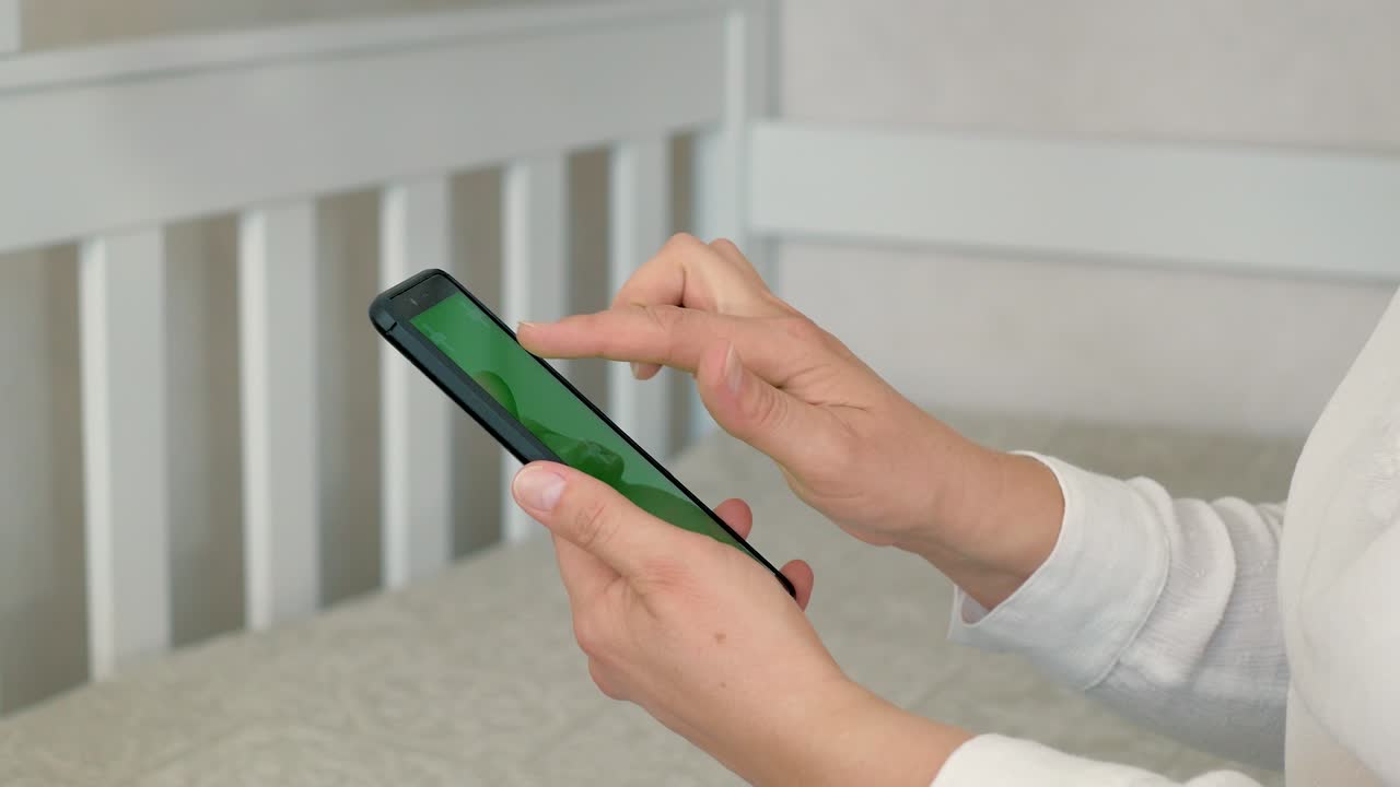 집에 있는 여성이 초록색 모형 화면의 스마트폰을 사용하고, 스와이프, 스크롤 제스처를 하고 있습니다. 소녀는 휴대전화를 사용하고 있습니다.