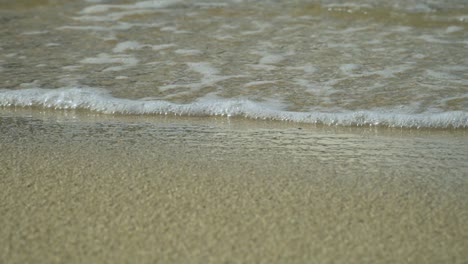 Suave-Ola-Rueda-Sobre-La-Orilla-Arenosa-Con-Espuma-Blanca-Y-Burbujas,-Cámara-Lenta