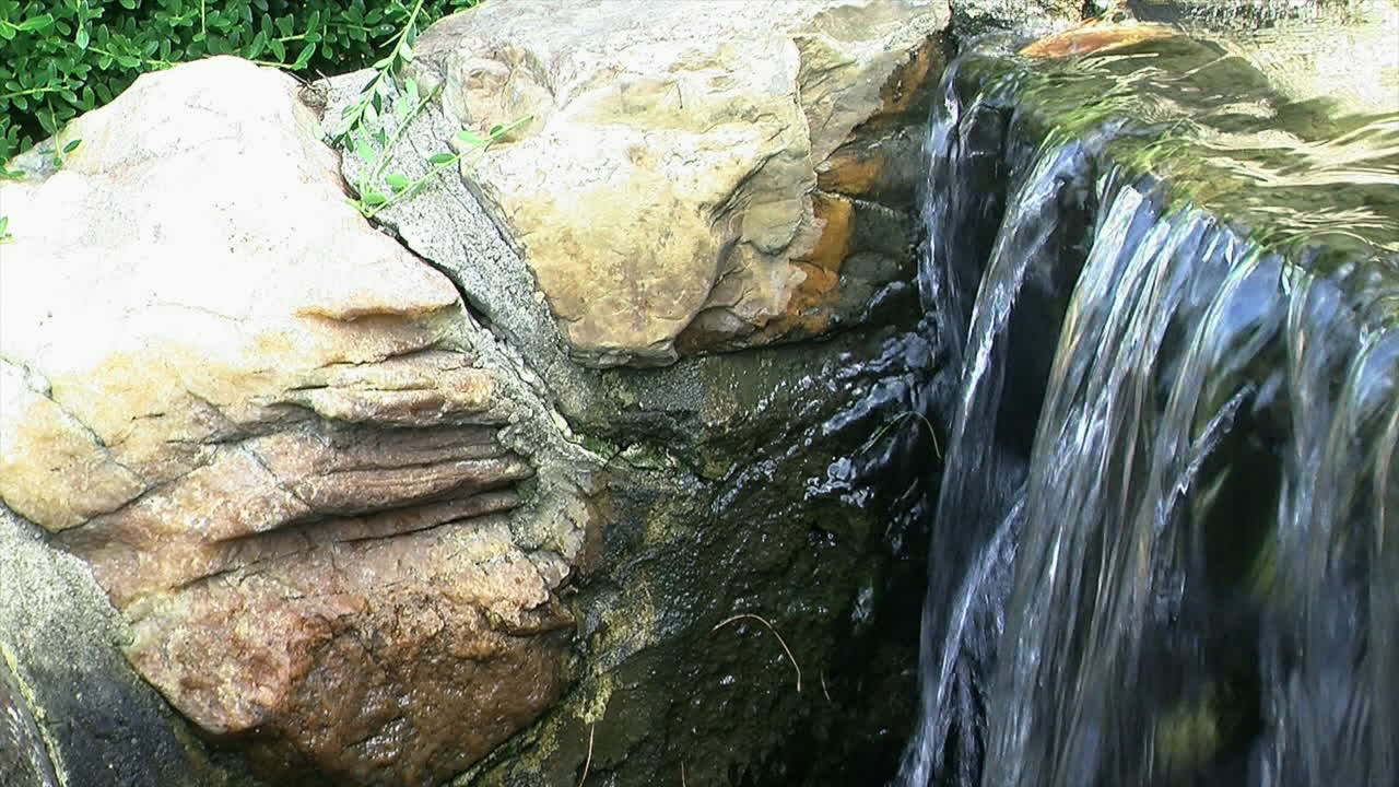 Water flows over the brink of an ornamental waterfall