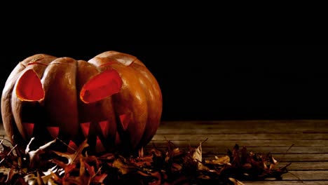 Halloween-pumpkin-with-maple-leaf-on-a-wooden-table-4k