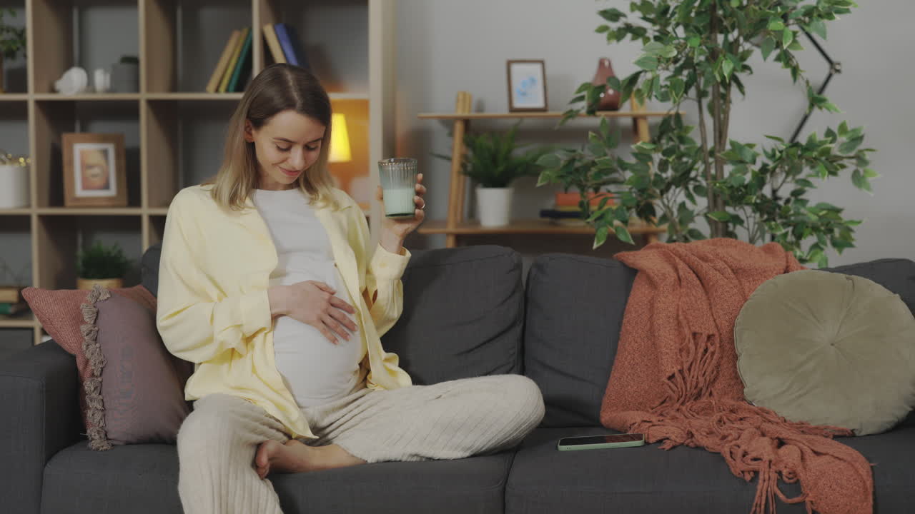 임신 한 여자 가 집 에서 우유 를 마시는 것