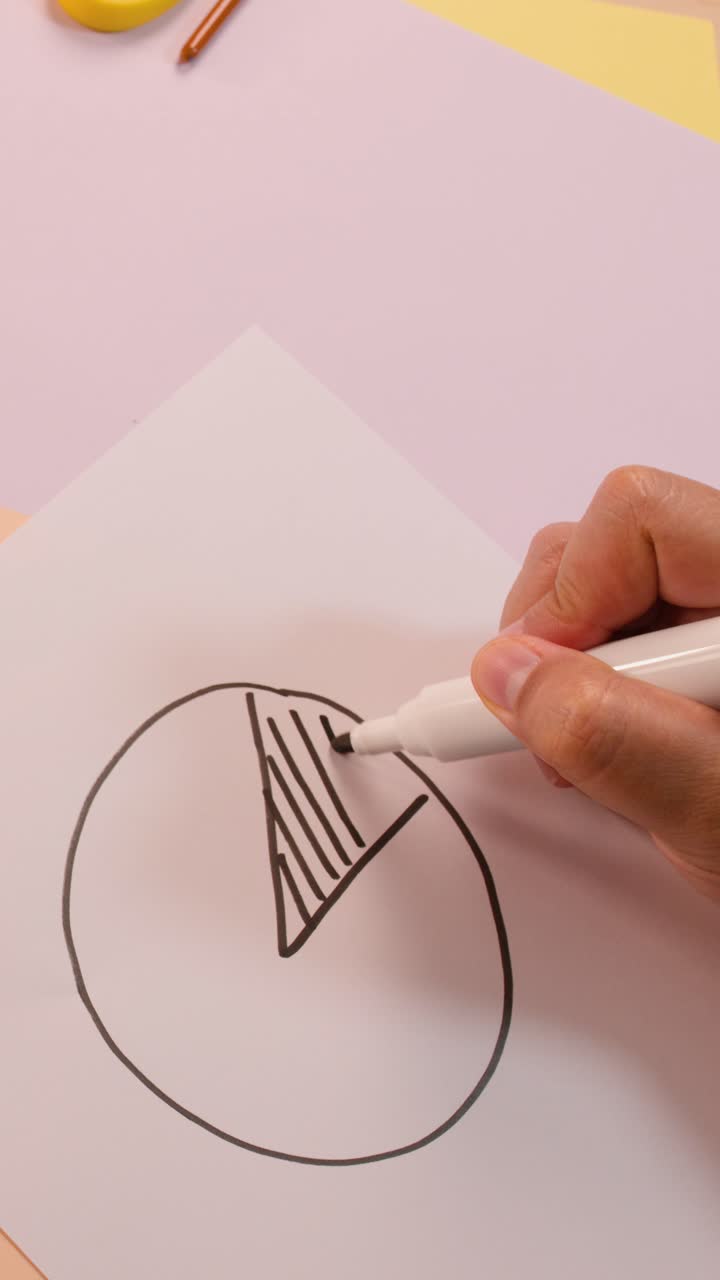 Una persona disegna un grafico a torta e simboli matematici su carta bianca, vista dall'alto, con luce pastello soffusa