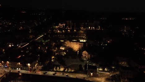 vista aérea giratoria en el sentido de las agujas del reloj del teatro romano iluminado por la noche - verona